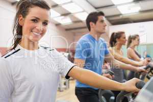 Smiling brunette with other people  on a step machine