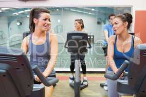 Two women talking  while training in a spinning class