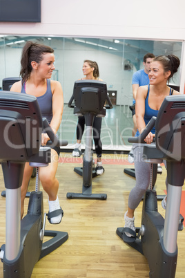 Women talking while training on exercise bike