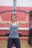 Smiling woman sitting at weight machine