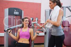 Woman using weights machine talking to friend