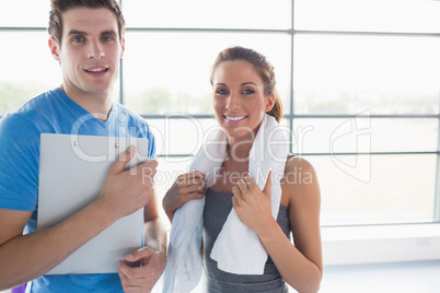 Woman holding a towel and trainer holding a clipboard smiling