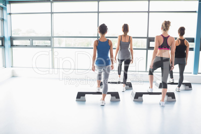 Four women stepping on boards