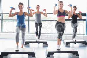 Four women lifting weights while doing aerobics