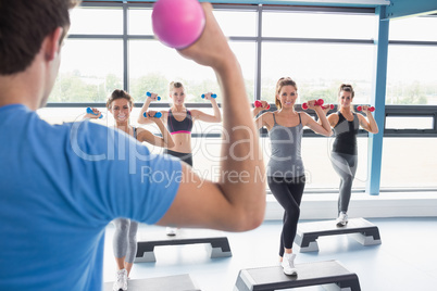 Trainer teaching his aerobicsclass while lifting weights