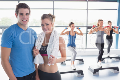 Woman and trainer smiling together in front of aerobics class