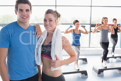 Trainer and woman smiling together while aerobics class taking p