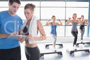 Women doing aerobics while trainer talking to woman