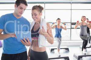 Trainer and woman talking while aerobics class lifiting weights