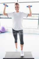 Female trainer lifting weights and doing aerobics
