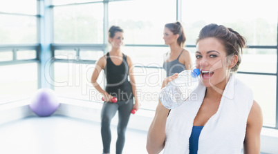 Woman drinking water while other women talking