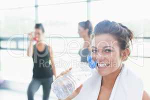 Women talking while another drinking water in fitness studio