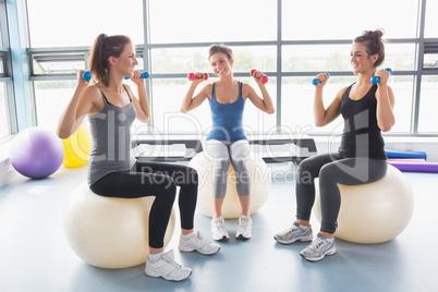 Three women lifting weights on exercise balls
