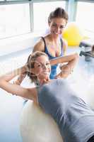 Woman doing sit ups on exercise ball with trainer