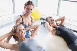 Two women doing sit-ups with trainer
