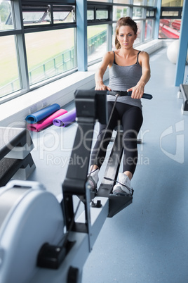 Brunette woman training on row machine