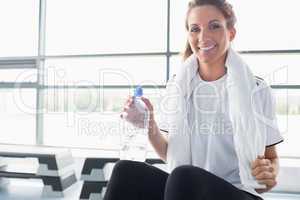 Woman drinking water and sitting on row machine