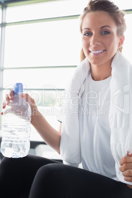 Woman with towel around her neck drinking water