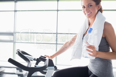 Woman holding a bottle and riding a exercise bike