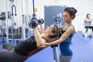 Woman lifting weights and her trainer