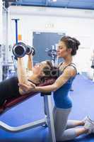 Concentrated trainer teaching woman lifting weights