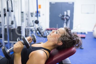 Concentrated woman lifting weights