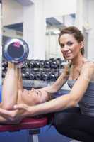 Trainer smiling with woman lifting weights