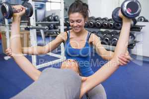 Trainer teaching woman lifting weights