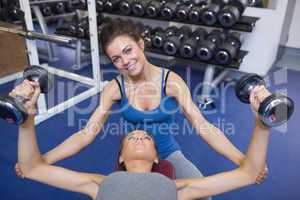 Woman teaching lifting weights and smiling