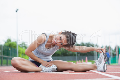 Smiling woman stretching on a track