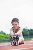 Smiling woman stretching on track