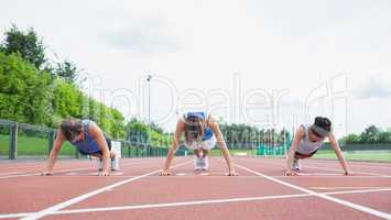 Three woman stretching on running track