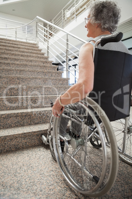 Elderly lady in wheelchair looking up stairs