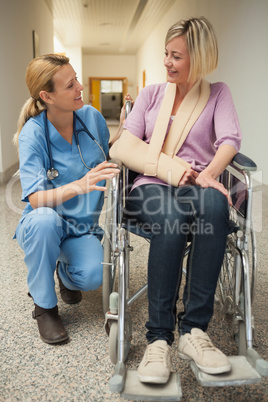 Nurse talking with patient in wheelchair with arm in sling