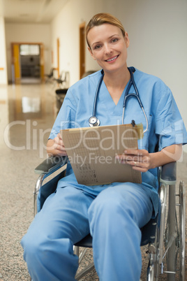 Smiling nurse checking her notes in a wheelchair