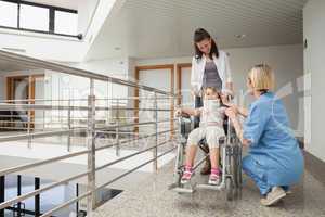 Nurse talking with child in wheelchair and neck brace with mothe