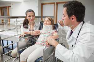 Mother and doctor crouch next to child in wheelchair with neckbr