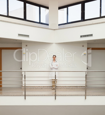Female doctor standing against wall by stairwell