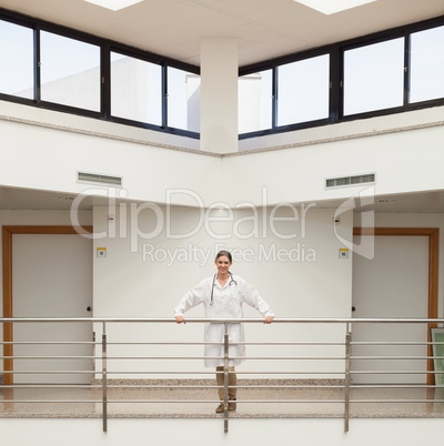 Smiling female doctor leaning on the railing