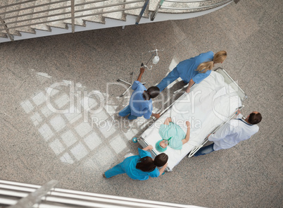 Three nurses and one doctor pushing a patient in a gurney