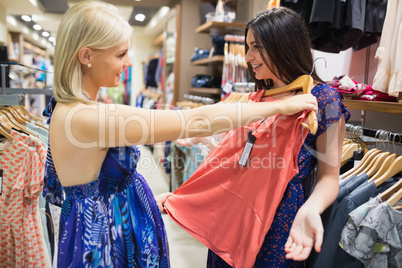 Woman holding shirt up to friend