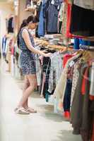 Woman is standing at the clothes rack  looking at clothes