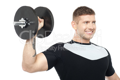 Muscular male showing his biceps by lifting heavy dumbbell