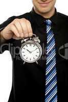 Business executive holding alarm clock. Cropped image