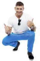 Cheerful young man showing double thumbs up