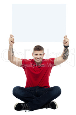 Casual man sitting on floor with billboard raised above head