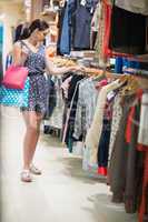 Woman is standing at the clothes rack holding bags