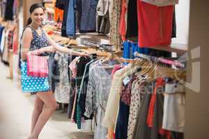 Woman searching through clothes rail while holding two bags