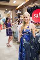 Smiling woman standing beside clothes rail