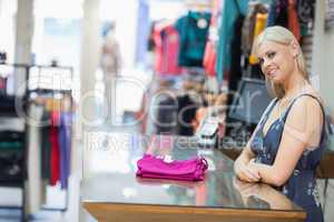 Woman smiling behind counter with folded clothes